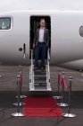 Бизнесмен, стоящий у входа в частный самолет в терминале — стоковое фото