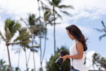 Jovem mulher revendo fotos na câmera digital na praia — Fotografia de Stock
