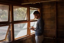 Side view of man writing note on diary at log cabin — Stock Photo