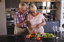 Seniorenpaar schneidet Gemüse in Küche zu Hause — Stockfoto