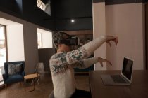 Mujer de negocios con auriculares de realidad virtual en la cafetería de la oficina - foto de stock
