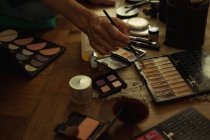 Primer plano de video blogger femenina con accesorios de maquillaje en casa - foto de stock