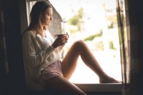 Nachdenkliche Frau beim Kaffee am Fenster zu Hause — Stockfoto