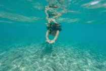 Женщина ныряет под водой в бирюзовом море — стоковое фото