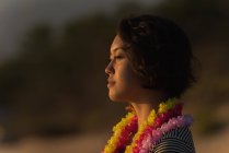 Красивая женщина в гирлянде стоит на пляже — стоковое фото
