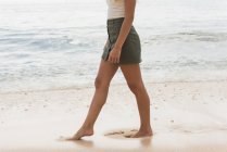 Partie basse de la femme marchant dans la plage par une journée ensoleillée — Photo de stock