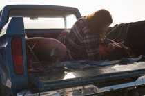 Casal de romances em uma caminhonete na praia em um dia ensolarado — Fotografia de Stock