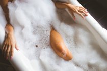 Metà sezione di donna che prende un bagno di bolla in bagno a casa — Foto stock