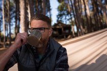 Крупним планом чоловік п'є каву, розслабляючись на гамаку — стокове фото