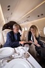 Gente de negocios discutiendo sobre tableta digital en jet privado - foto de stock