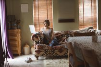 Женщина использует ноутбук на диване в гостиной дома — стоковое фото