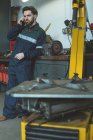 Mechanic talking on mobile phone in repair garage — Stock Photo
