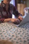 Seção média de mulher usando laptop na mesa em casa — Fotografia de Stock