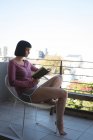Женщина читает книгу на балконе дома — стоковое фото