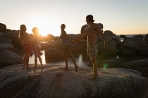 Two couples dancing on a rock in the beach at dusk — Stock Photo