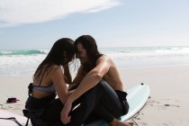 Surfer couple romancing in the beach on a sunny day — Stock Photo