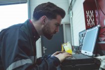 Aufmerksamer Mechaniker mit Laptop in Reparaturwerkstatt — Stockfoto