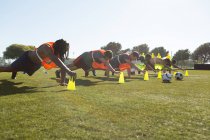 Игроки, тренирующиеся при поддержке конуса в поле — стоковое фото