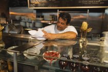 Homme boulanger écriture sur un bloc-notes au comptoir dans le café — Photo de stock