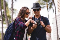 Couple reviewing pictures on digital camera in city street — Stock Photo