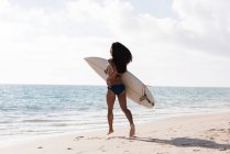 Жінка працює з дошки для серфінгу в пляжу сонячний день — стокове фото