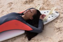 Femme dormant sur une planche de surf à la plage par une journée ensoleillée — Photo de stock