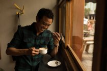 Усміхнений бізнесмен розмовляє по мобільному телефону, маючи каву в кафе — стокове фото