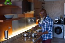 Старший мужчина готовит дома на кухне — стоковое фото