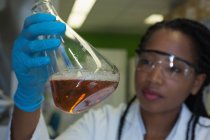 Scientifique vérifiant une solution en fiole conique au laboratoire — Photo de stock