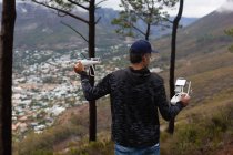 Visão traseira do homem operando um drone voador no campo — Fotografia de Stock