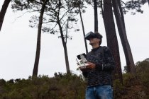 Homem operando um drone voador enquanto usa fones de ouvido de realidade virtual no campo — Fotografia de Stock