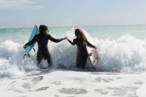 Vista traseira do surfista casal surfar na praia — Fotografia de Stock