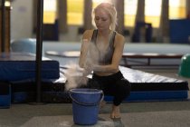 Sportswoman dusting her hands with chalk powder at fitness studio — Stock Photo
