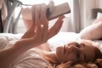 Жінка використовує мобільний телефон в спальні вдома — стокове фото