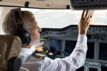 Чоловічий пілот натискає кнопку в приватній кабіні — стокове фото