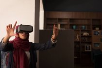 Mujer de negocios en hijab usando auriculares de realidad virtual en la cafetería de la oficina - foto de stock