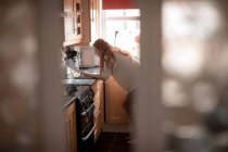 Femme utilisant un ordinateur portable dans la cuisine à la maison — Photo de stock