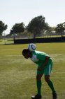 Jugador de fútbol practicando con una pelota en el campo - foto de stock