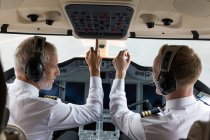 Два пілоти-чоловіки натискають кнопку в приватній кабіні — стокове фото