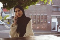 Belle femme hijab urbain parlant sur téléphone mobile au café — Photo de stock