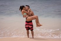 Couple s'embrassant sur la plage par une journée ensoleillée — Photo de stock