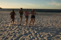Женщины-волейболистки бегают вместе по пляжу — стоковое фото