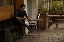 Бізнесмен пише на щоденнику з ноутбуком на столі в кафе на тротуарі — стокове фото