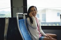Усміхнена жінка розмовляє на мобільному телефоні в автобусі — стокове фото
