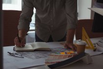 Средняя секция архитектора пишет заметку о дневнике в офисе — стоковое фото