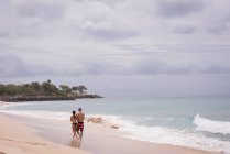 Paar spaziert an einem sonnigen Tag gemeinsam am Strand — Stockfoto