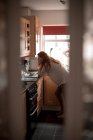 Mujer usando el ordenador portátil en la cocina en casa - foto de stock