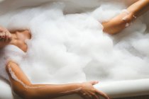 Donna che fa un bagno di bolle in bagno a casa — Foto stock