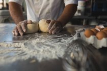 Mid section of male baker preparing dough in bakery shop — Stock Photo
