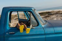 Donna rilassante con i piedi su in un pick-up in spiaggia — Foto stock